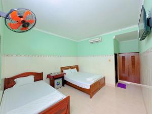 a bedroom with two beds and a fan on the wall at Anh Linh Guest House in Mui Ne