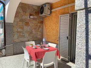 a table with white chairs and a red table cloth at BenitiKe House in Cala Gonone +50 photos