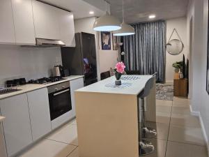 a kitchen with white cabinets and a vase of flowers on a counter at Sibaya's Luxurious Apartment in Coral Point in Umhlanga