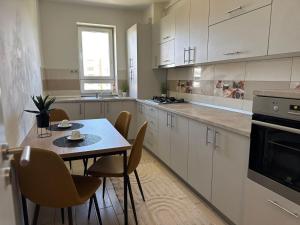 a kitchen with white cabinets and a table and chairs at Avantgarden Studio Brasov in Braşov +8 photos