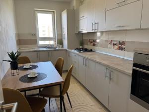a kitchen with white cabinets and a table and chairs at Avantgarden Studio Brasov in Braşov