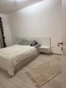 a white bedroom with a bed and a rug at Avantgarden Studio Brasov in Braşov
