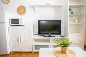 a living room with a tv on a white entertainment center at Casa Luz del Carmen - Terraza, Primera Línea in Barbate