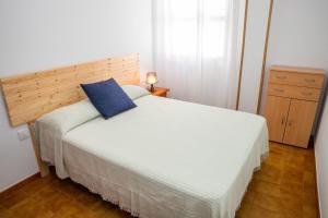 a bedroom with a bed with a blue pillow on it at Casa Luz del Carmen - Terraza, Primera Línea in Barbate