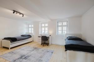 a bedroom with two beds and a desk and windows at Stilvolles Wohnen am Ziegeltor - Für Gruppen, Pärchen und Singles in Amberg