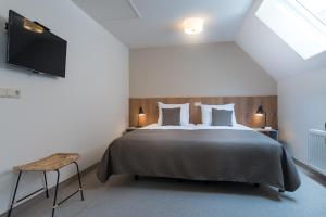 een slaapkamer met een bed en een flatscreen-tv bij Leut logies in Oost-Vlieland +16 foto's