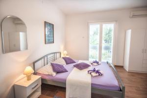 a bedroom with a bed with purple pillows and a mirror at Apartments Srijemsi in Mlini