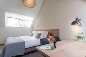 Schlafzimmer mit einem Bett und einem Holztisch in der Unterkunft Leut logies & Boutiquehotel het Eiland in Oost-Vlieland