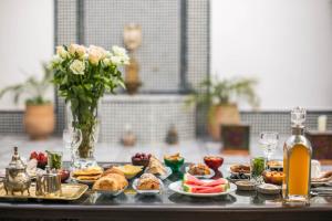 a table with plates of food and a vase of flowers at Riad Amor - Suite & Spa in Fès