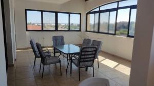 a dining room with a table and chairs and windows at 3-bedroom penthouse in Larnaka