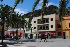 a group of people walking down a street with palm trees at Hostal Casa Amaya in Vallehermoso