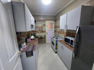eine kleine Küche mit weißen Schränken und einem Kühlschrank in der Unterkunft شقة مفروشة للإيجار اليومي في كمبوند جاردينيا سيتي in Kairo