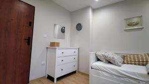 a white bedroom with a bed and a dresser at Apartament Wysoka 580 z prywatną łazienką in Bielawa