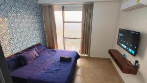 a bedroom with a purple bed and a large window at Swimming Pool with Full Equipped Studio Apartment in Noida
