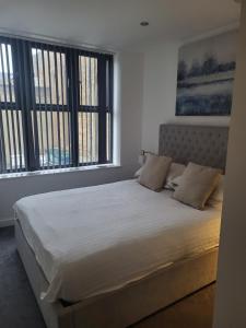 a bedroom with a large bed with two windows at Ramsgate Retreat 2 Bed Coastal Stay in Ramsgate