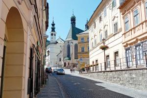 a city street with buildings and a car on the road at Apartmán Veles Banská Štiavnica in Banská Štiavnica
