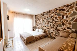 a bedroom with a stone wall with a bed and a couch at Stefanidis studios in Stavros