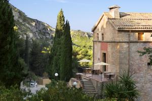 an old stone building with tables and umbrellas at Petit Hotel Hostatgeria La Victoria in Alcudia