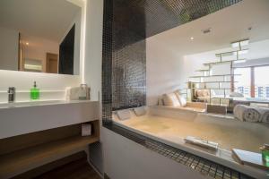 a bathroom with a tub and a sink and a mirror at Biohotel Organic Suites in Bogotá