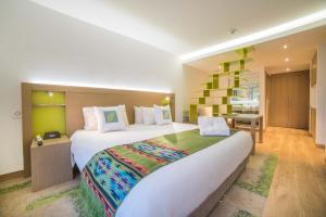 a hotel room with a large bed and a desk at Biohotel Organic Suites in Bogotá