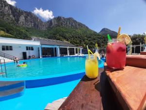 two drinks on a table next to a swimming pool at Artemis in Băile Herculane