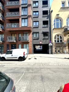 Una camioneta blanca estacionada frente a un edificio en Dubois 7 Apartment - Self Check-In 20h - LIFT, en Wroclaw