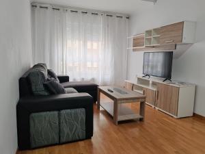 a living room with a couch and a tv and a table at Os Garitos in Ribadeo