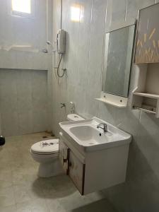 Un baño blanco con lavabo e inodoro. en FUBON World, en Vientiane