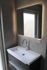 a bathroom with a white sink and a mirror at De Strandloper Zeeland, Studio nabij strand 3km in Koudekerke