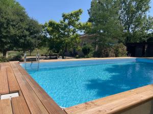 a large swimming pool with a wooden deck next to a house at Maison de campagne / piscine privée in Villeréal