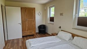 a bedroom with a bed and a door and a chair at Ferienwohnung Seeblick in Altefähr