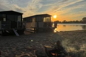 a boat on the shore of a lake at sunset at Holiday Houseboats in Lith