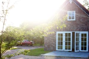 a red brick house with a white door at Appartement Het Brummelhof in Vrouwenpolder