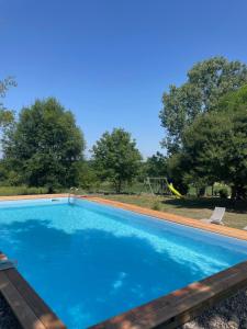 a swimming pool with a playground in the background at Maison de campagne / piscine privée in Villeréal +12 photos