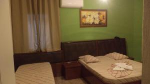 een kleine slaapkamer met 2 bedden en groene muren bij Hotel New Plaza in São Bernardo do Campo