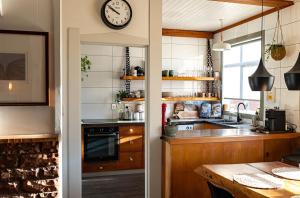a kitchen with a clock on the wall and a table at Drifting Sands Beachfront Retreat in Hokitika