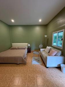 ein Schlafzimmer mit einem Bett und einer Couch in der Unterkunft Well Living Guesthouse Khaolak in Khao Lak