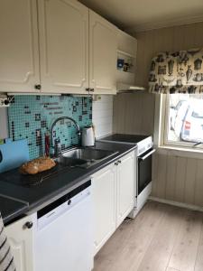 Una cocina con gabinetes blancos y un fregadero y una ventana. en Midnight Sun Road, en Bodø