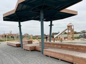 a playground with wooden benches in a park at Ferienhaus Nordseejuwel in Friedrichskoog-Spitze