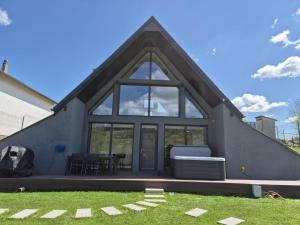 Muntele CacoveiCBN Cabana的一栋灰色的房子，有一扇大窗户和一张桌子。