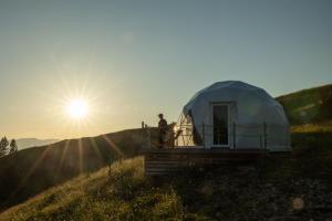 a man standing outside of a tent in a field at Stargazing Glamping Domes Golte in Mozirje