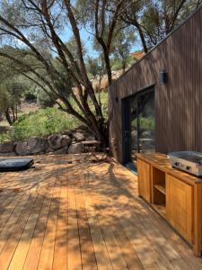 a wooden deck with a tree in front of a building at Lodges sous les oliviers in Propriano