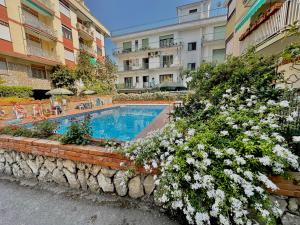 a swimming pool with flowers in front of a building at Large family appartament with pool in Sorrento
