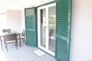 a room with green doors and a table with chairs at Villa Luger 2 Dachgeschoss in Rogoznica
