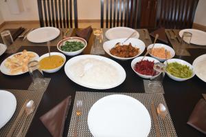 a table with plates and bowls of food on it at Hide Out Hills Bungalow in Nuwara Eliya