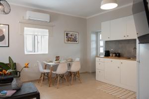 a kitchen with white cabinets and a table and chairs at Mika's Loft - Pylos in Pylos