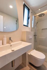 a bathroom with a sink and a toilet and a mirror at Lucciola Boutique Rooms in Budva +24 photos