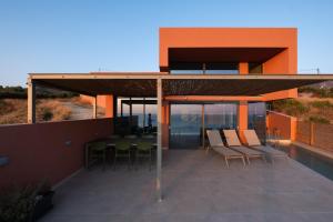a patio with chairs and a table on a roof at Casa Tarrha- Beachfront Villa with Heated Pool in Livadia