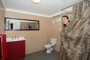 a woman in a leopard print shower curtain in a bathroom at Backpackers In Paradise Under 45's Hostel in Gold Coast