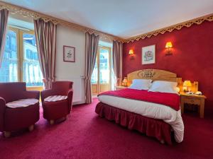 a bedroom with a large bed with red walls and windows at Hôtel Le Bois Joli in Cauterets